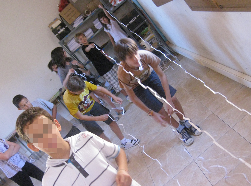 Alumnos comprobando quién ha conseguido transformar un hoja de papel en la tira de papel más larga.